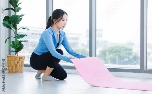 Free Download Asian young beautiful happy smiling cheerful woman active sport in sportswear sit preparing laying out a yoga mat exercise pilates stretching training in bright fitness gym healthy wellness lifestyle - GFXLoad