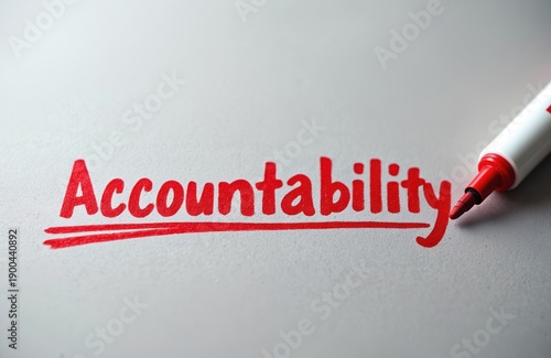 The word Accountability is written in bold red marker on white paper with a red line underneath. A red marker pen is positioned on the right side of the word.
