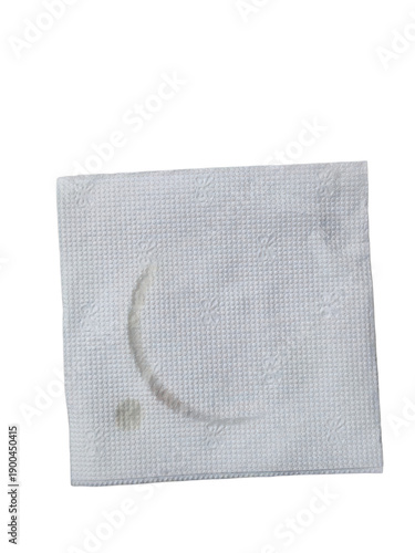 Close-up of a coffee stain on a textured white napkin against black background