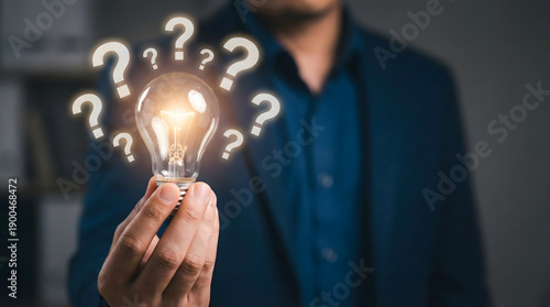 Person,hand,holding,light,bulb,surrounded,by,question,marks,representing,creative,thinking,problem,solving,finding,new,business,ideas,innovative,inspiration,and,brainstorming,solutions