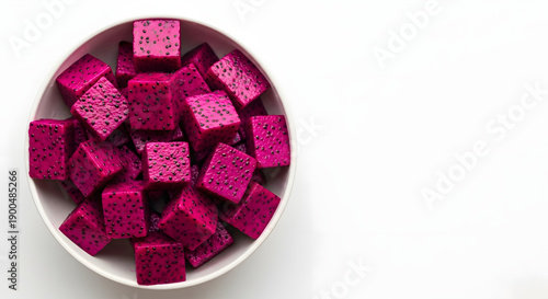 A white bowl filled with vibrant, cubed magenta dragon fruit, showcasing its striking color and unique texture against a clean white background