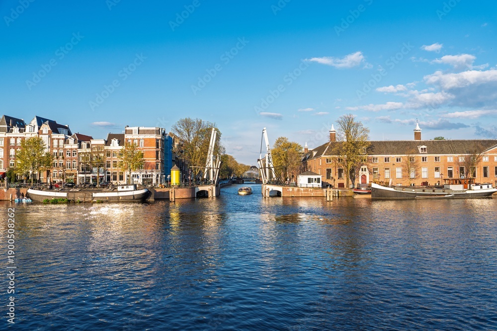 Obraz premium Experience Amsterdam s charm with this beautiful canal view showcasing historic architecture and houseboats. A perfect image to highlight the city s unique culture and tranquility.