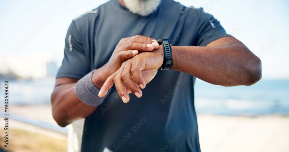 Fototapeta premium Old man, hands and smart watch by beach with fitness app, heart rate tracker and monitor performance. Senior person, runner and workout break by ocean with tech, check pace and wellness notification.