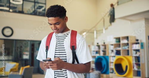 Education, phone and typing with boy student on high school campus for communication or study. App, learning and text message with teen learner in corridor for classroom schedule or timetable