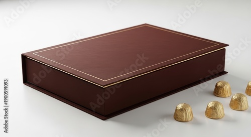 Luxury chocolate gift box with gold foils beside it on a white surface viewed from an angle