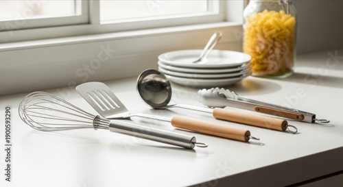 Collection of stainless steel kitchen utensils with wooden handles in sunlight