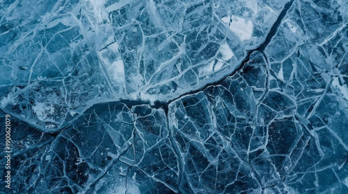 Close-up view of intricate cracks and fractures in a sheet of blue ice, showcasing its delicate and complex natural patterns.