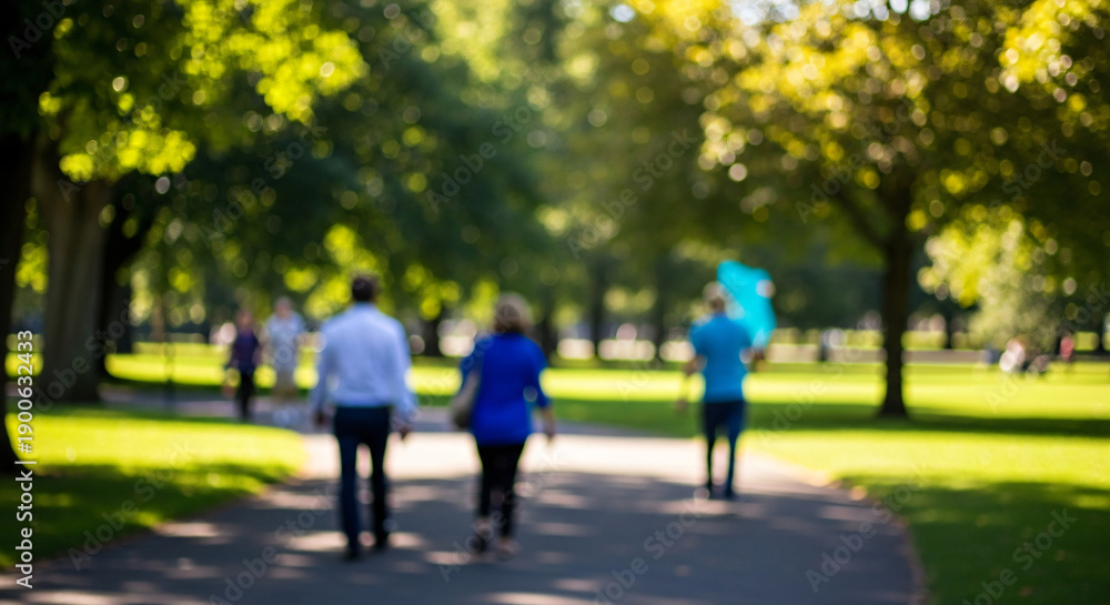 Obraz premium Out of focus view of people strolling through a lush green city park on a bright summer day with a beautiful bokeh background