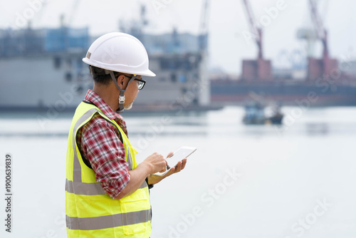 A professional logistics engineer monitoring and commanding cargo port operations from a shore-based office using a high-speed digital network. Concept of smart logistics, 5G industrial automation, an