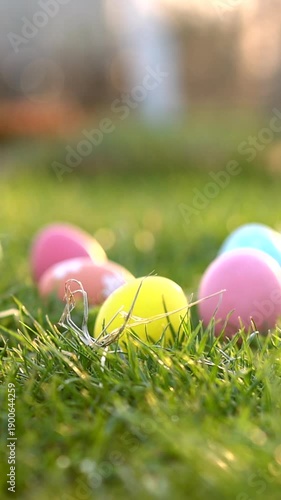 Easter eggs on green spring grass with basket in sunlight. Vertical