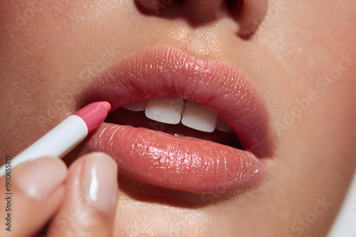 Woman applying pink lip gloss.