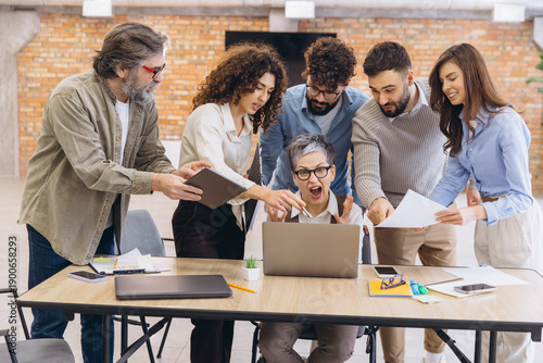 Bilde på lerret Stressed woman screaming at laptop during chaotic office meeting with team membe