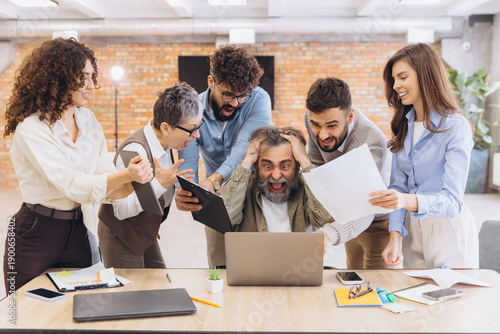 Stressed businessman receiving pressure from coworkers, feeling burnout and overwhelmed by a frantic workplace deadline