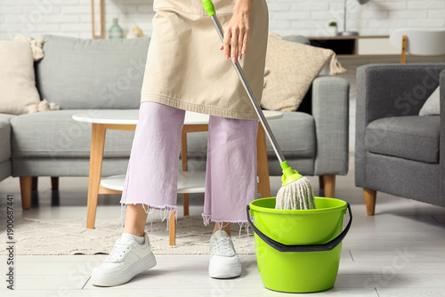 Young woman washing floor w...