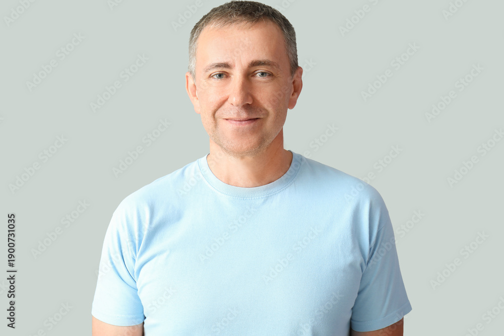 Fototapeta premium Portrait of smiling mature man on grey background