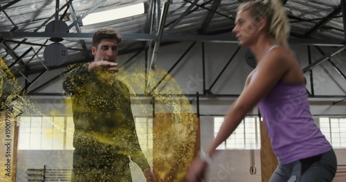 Canvas-taulu Coaching trainer guiding trainee in purple tank lifting in warehouse gym with ri