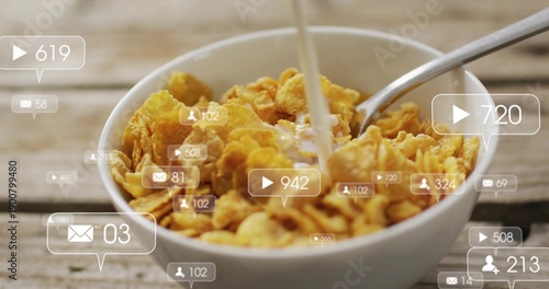 Pouring milk into white bowl of cornflakes on worn wooden table, spoon, social overlays floating