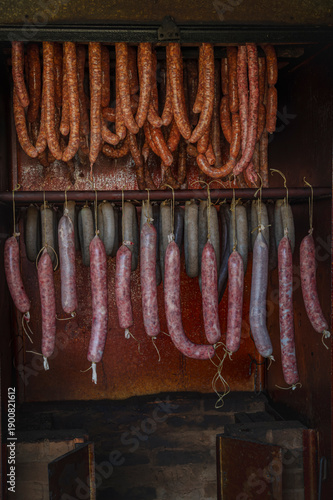 Authentic traditional meat processing with sausages and liver sausage hanging in a smokehouse.