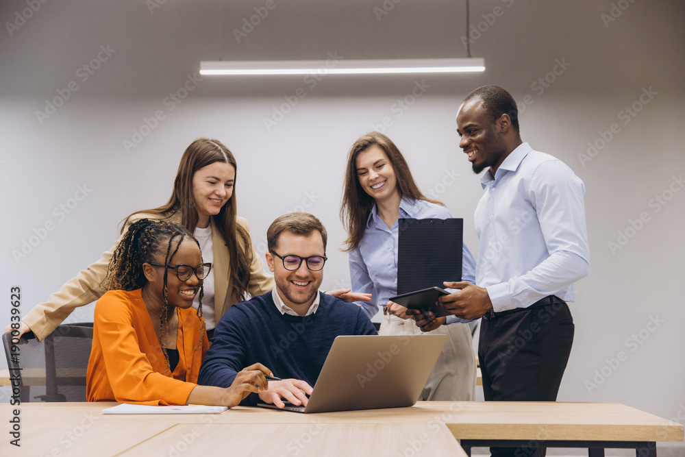 Obraz premium Diverse team collaborating, sharing insights during business meeting, working on laptop in contemporary workspace, brainstorming project strategy