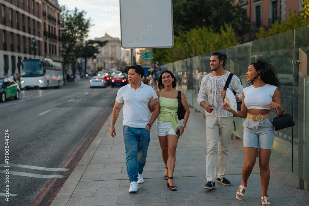 Fototapeta premium Four friends walk together on a Madrid street, enjoying a sunny urban day