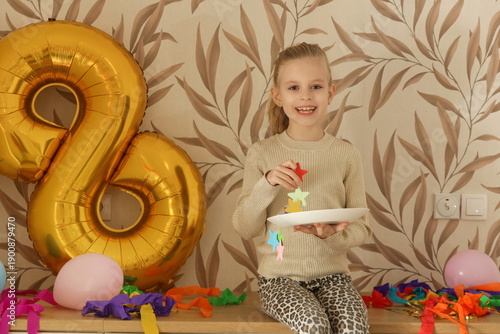 Fotografia Happy Little Girl Taking Photo Next to Golden Number Eight Balloon After Birthda