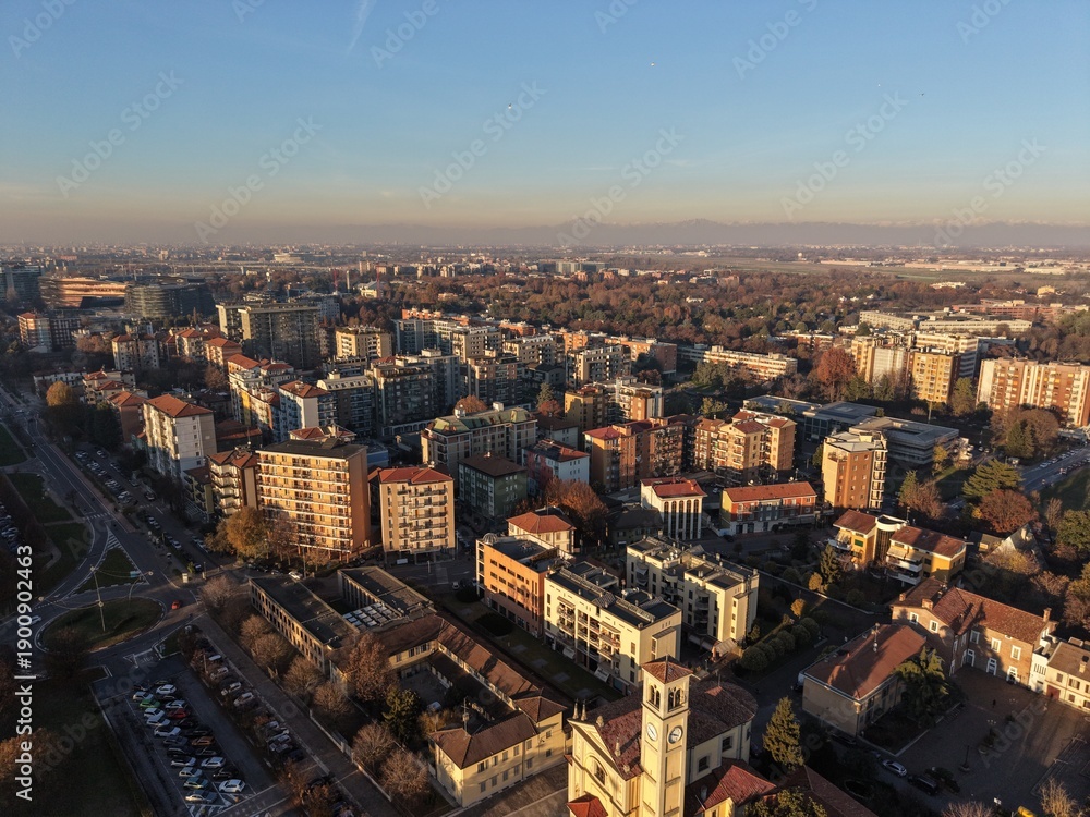Fototapeta premium A sprawling cityscape unfolds beneath a clear, blue sky, showcasing a blend of residential buildings, and open spaces, offering a glimpse into the rhythm of urban life.