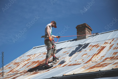 Mężczyzna malujący zardzewiały dach