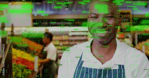 Smiling clerk in striped apron arranging produce in store aisle with green code overlay, copy space