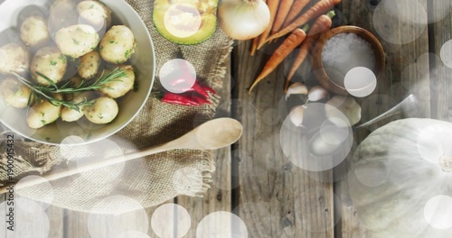 Showing white bowl of seasoned potatoes with rosemary on rustic table, avocado, carrots, copy space