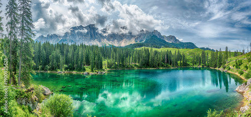 The emerald green Lake Carezza reflecting Latemar mountain, Dolomites, Italy