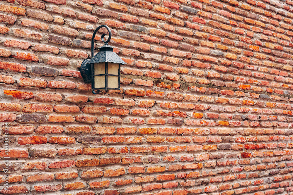 Naklejka premium Light fixture on brick wall in a rustic setting at an outdoor location