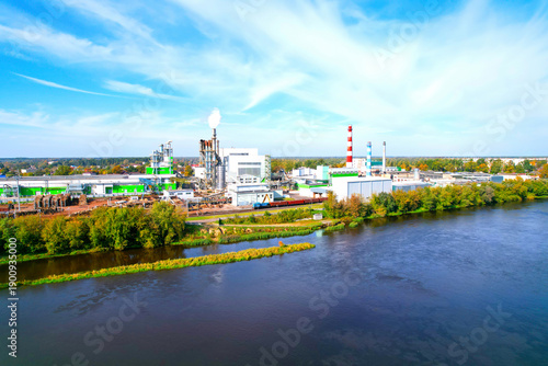 Woodworking plant at river, aerial view. Wood processing plant. Factory smoke stacks. Industrial timber production, wood products. Timber manufacturing factory, warehouse storage for logs.
