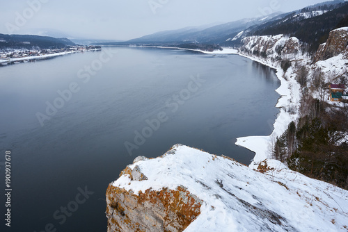 Yenisei river view from Karaulnensky cliff in winter. Wide scenic landscape with water, snow, and forest. Travel destination Siberia.