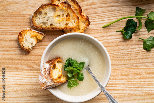 Cauliflower cream soup with grilled bread and cilantro on rustic wooden background