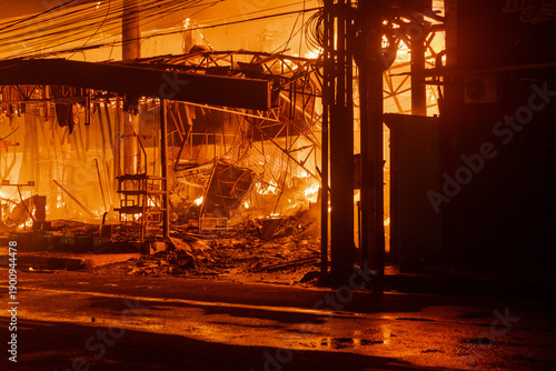 Devastating structure fire burns intensely in an Cilacap urban landscape with a dark atmosphere. Suitable for emergency response materials.