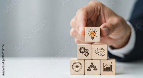 Hand arranging wooden blocks with icons representing business strategy and innovation concepts