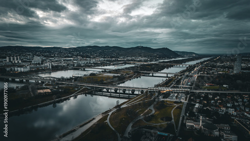 aerial cinematic drone photo of vienna Austria danube river with bridges covering the river with mountains in the distance and cityscape below at sunset