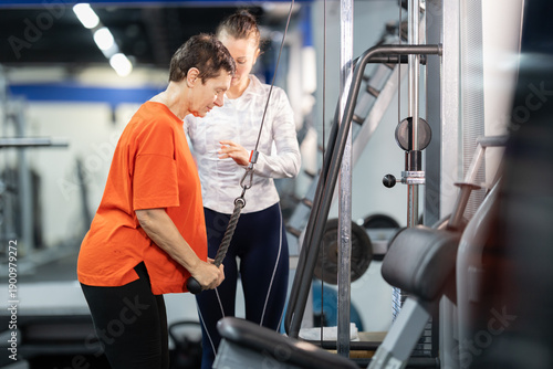 Obraz na plátně Senior woman training with personal trainer at gym