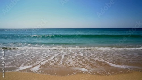 Serene Beach Waves Under Clear Blue Sky.