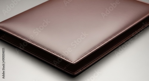 Close-up of a brown leather portfolio on a white surface.