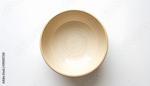 Empty beige ceramic bowl viewed from above on white surface, smooth glossy interior with concentric circular patterns.