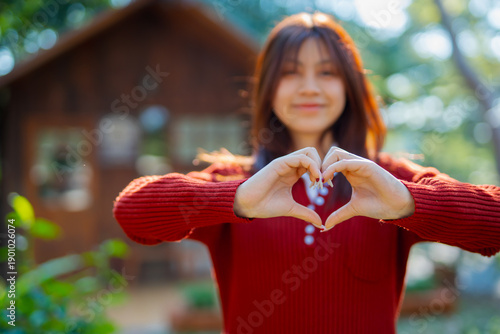  A front view of a cute girl making a heart shape with her hands. (Expression)