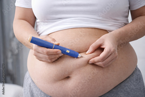 Overweight woman injecting diabetes medication with injector pen.