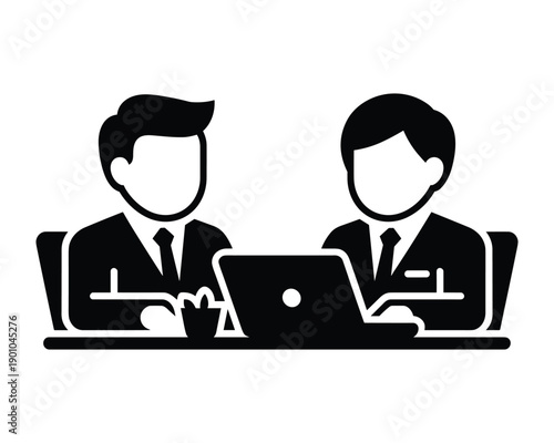 Two businessmen in suits collaborating at a desk with a laptop computer between them
