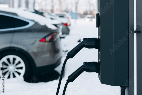 Electric car charging station with plugged cable in winter city.