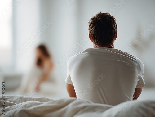 Man sitting on bed seen from behind, woman blurred in background. Scene representing male fertility problems, low libido, and emotional distance in relationship