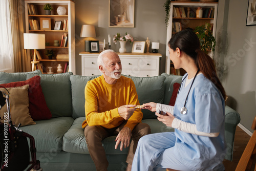 Bilde på lerret A home health nurse interacts with a senior man in his living room, providing care and discussing medication