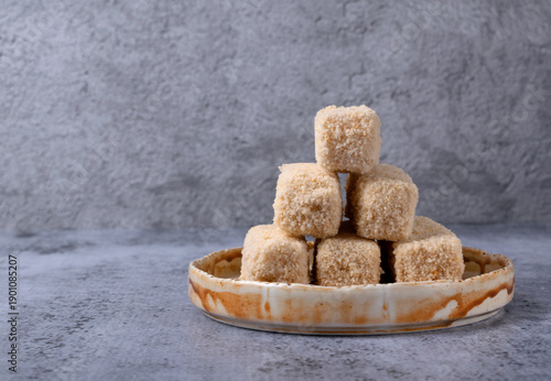 Frozen breaded fish sticks on a ceramic plate on a gray background. Semi-finished product for frying