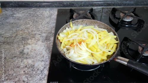Potatoes and onions are fried in a frying pan