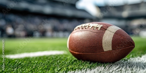 A leather football rests on the sideline of a stadium field